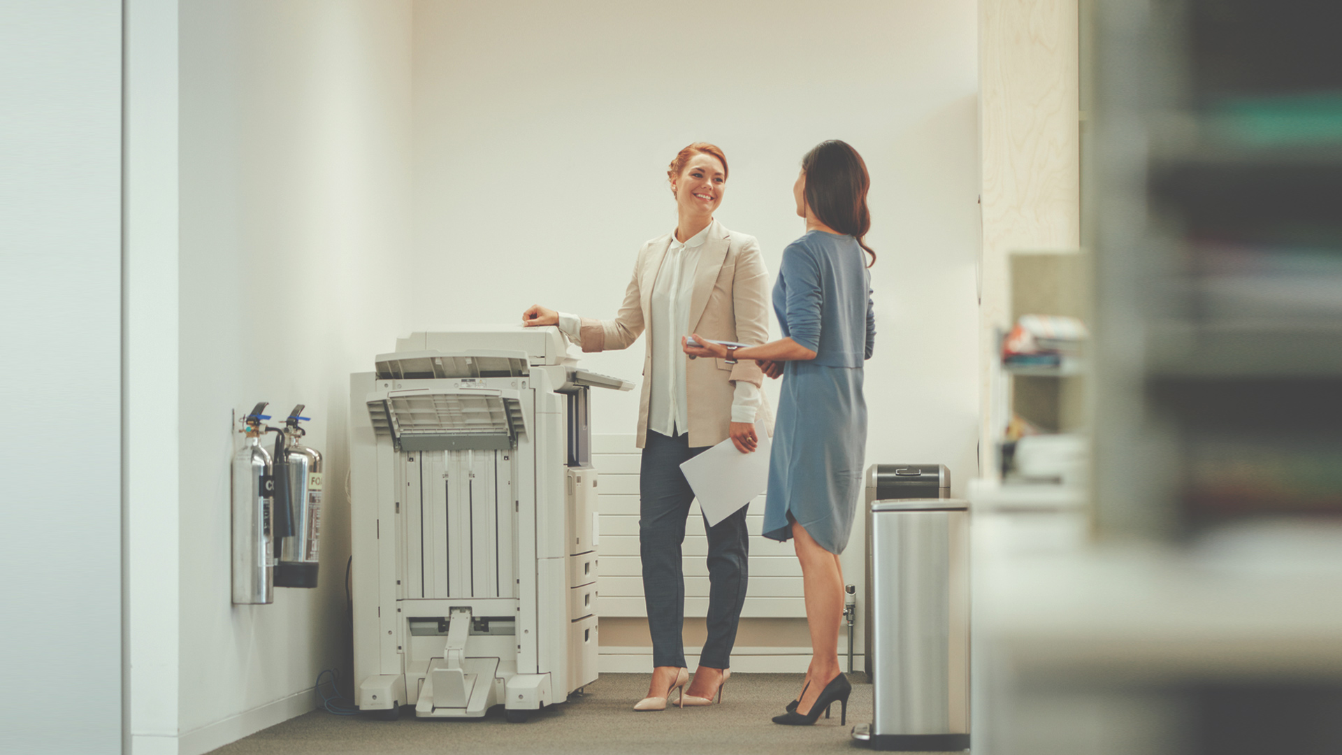 Two women interacting by the copy machine